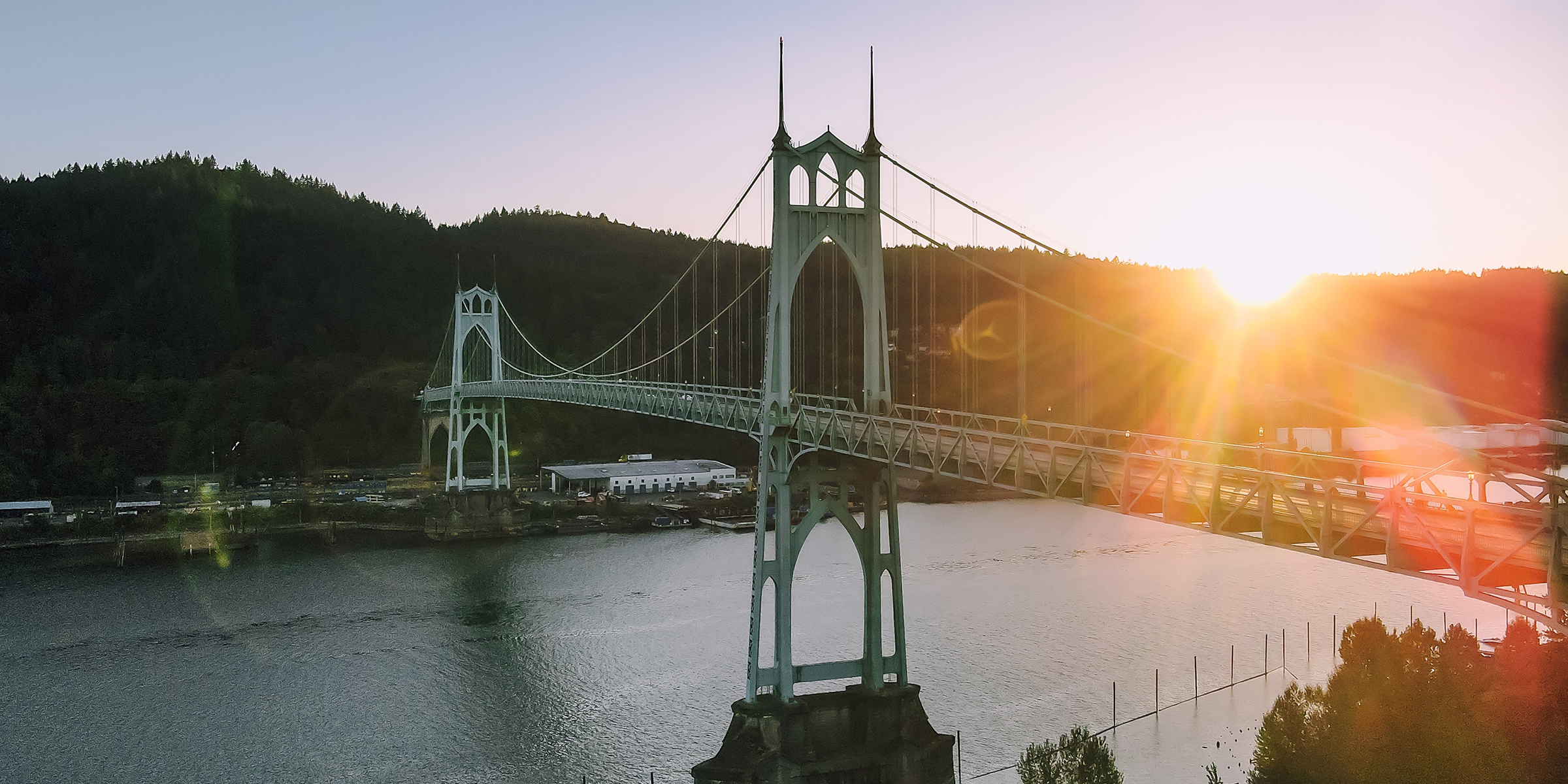 View from above of St John's large steel suspension bridge spanning Willamette River with sun setting in background